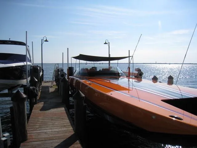 Slide: The Image of 2024 Mystic Powerboats C4000 docked, sleek orange design, sunlit water backdrop. - 18