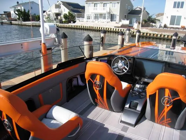 Slide: The Image of 2024 Mystic Powerboats C4000 interior with orange seats, sleek dashboard, and waterfront view. - 8