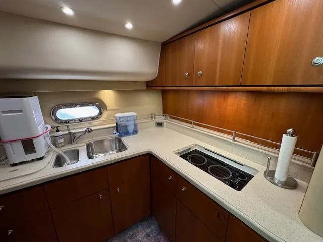 Slide: The Image of 2007 Tiara Yachts 4300 Sovran kitchen with wood cabinets, sink, and stovetop. - 43