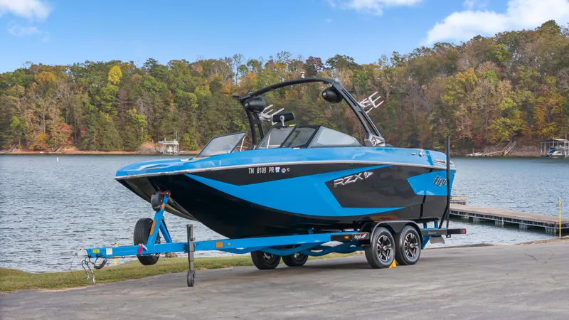 Slide: The Image of 2021 Tigé 23RZX boat on trailer by a scenic lake. - 2