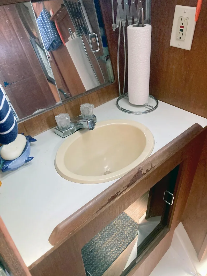 Slide: The Image of Small bathroom sink area in a 1983 Hunter 34 sailboat, featuring a mirror and paper towel holder. - 15