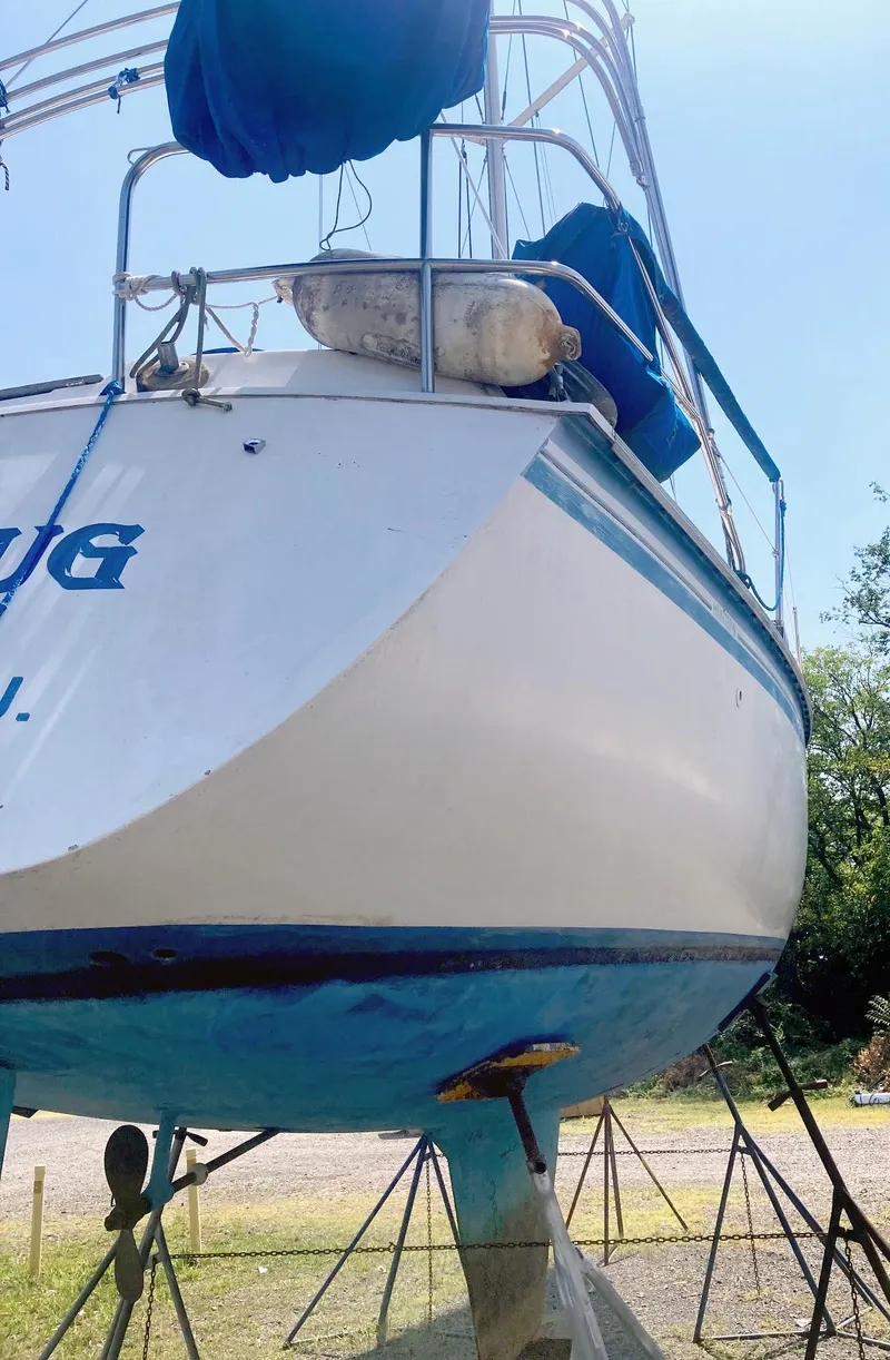 Slide: The Image of 1983 Hunter 34 sailboat on stands, blue and white hull, outdoor setting. - 4