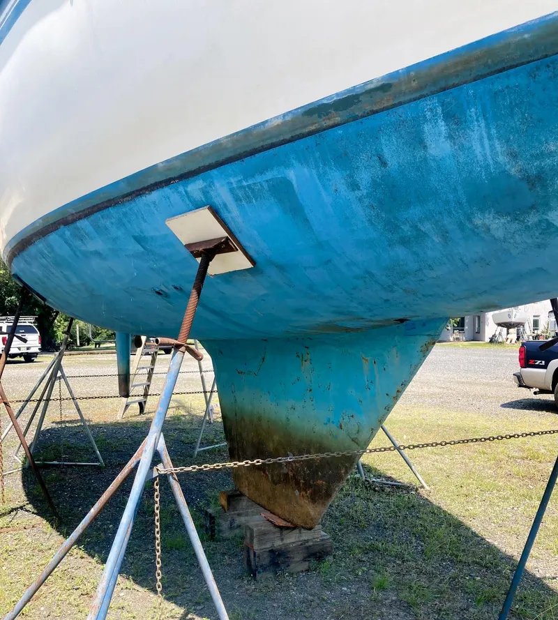 Slide: The Image of 1983 Hunter 34 sailboat hull on stands, blue and white, in a boatyard. - 6