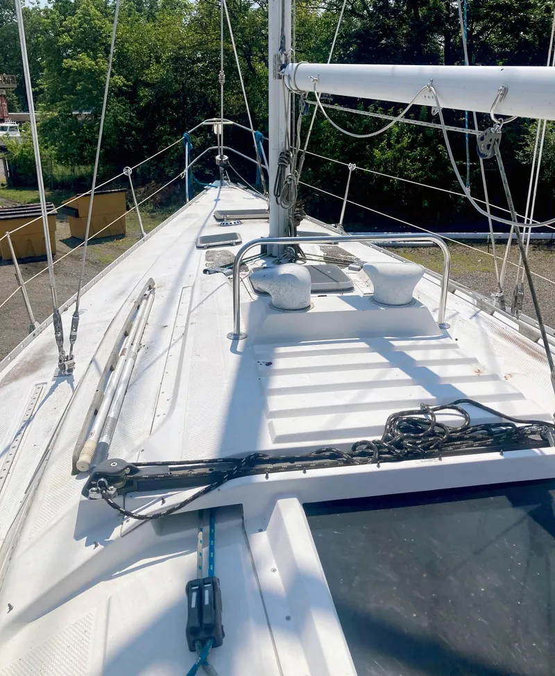 Slide: The Image of 1983 Hunter 34 sailboat deck with rigging and mast, surrounded by greenery. - 7