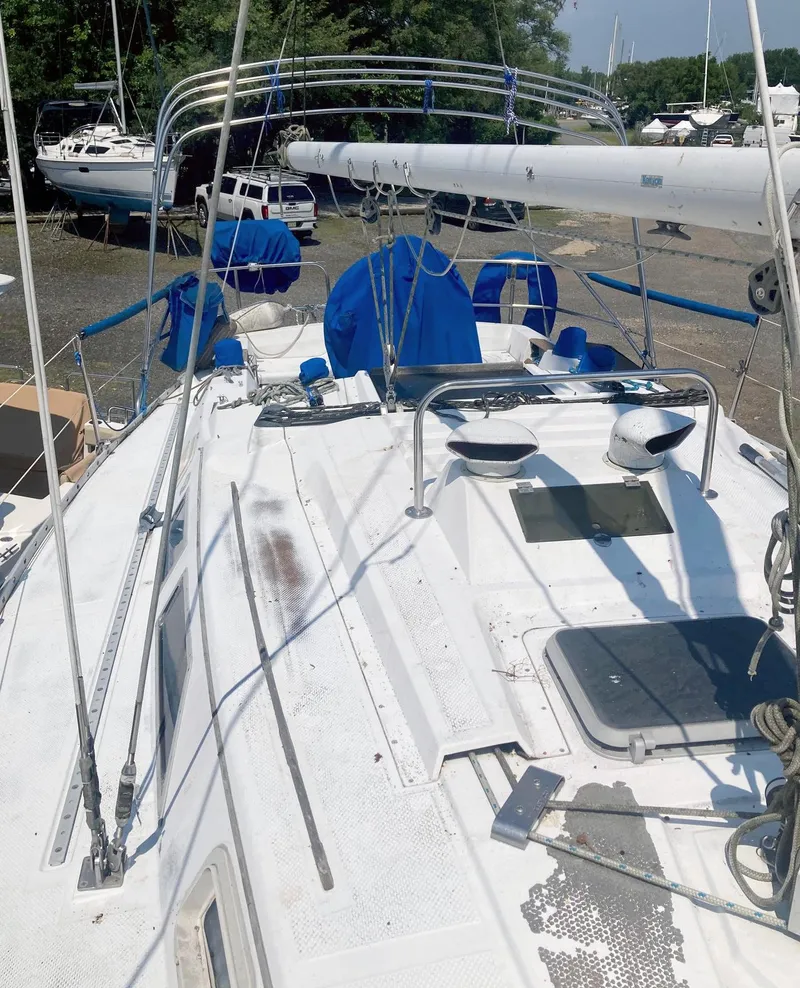 Slide: The Image of 1983 Hunter 34 sailboat deck with blue covers and rigging in a boatyard. - 8