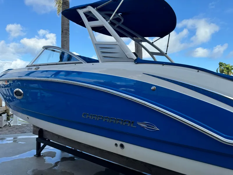Slide: The Image of 2017 Chaparral 250 Suncoast boat with blue and white exterior under a clear sky. - 1