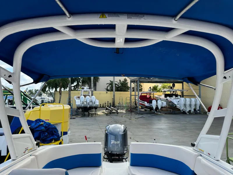 Slide: The Image of 2017 Chaparral 250 Suncoast boat with blue canopy and outboard motor in marina. - 21