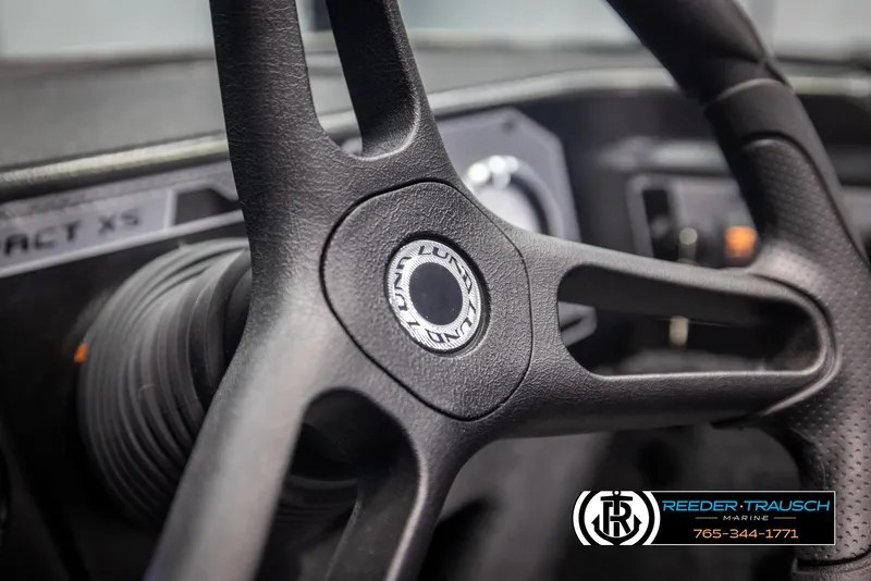 Slide: The Image of Steering wheel of 2025 Lund 1875 Impact XS boat, featuring Reeder-Trausch Marine branding. - 26