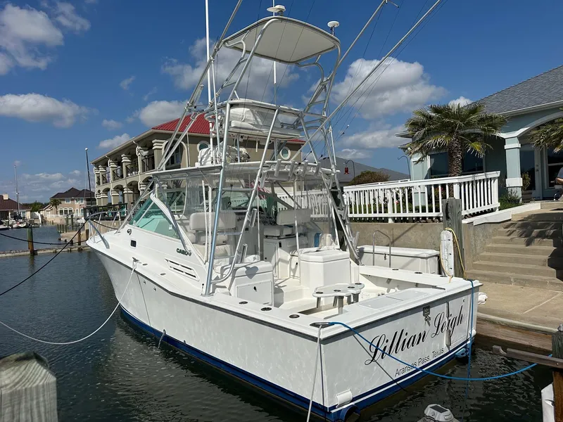 Slide: The Image of 2000 Cabo 31 Express boat docked in a marina under a clear blue sky. - 1