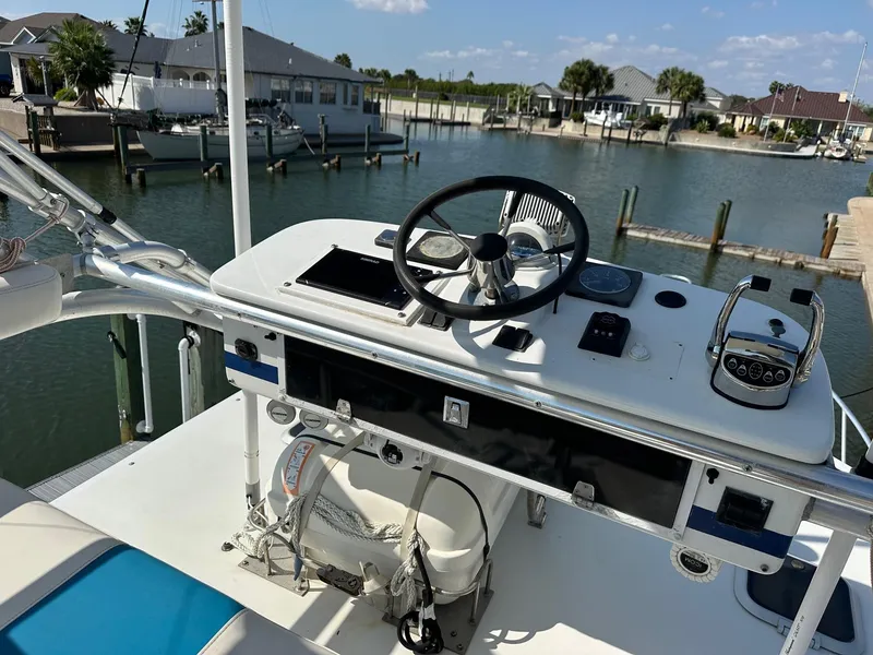 Slide: The Image of 2000 Cabo 31 Express boat helm with steering wheel and controls, docked in a marina. - 10