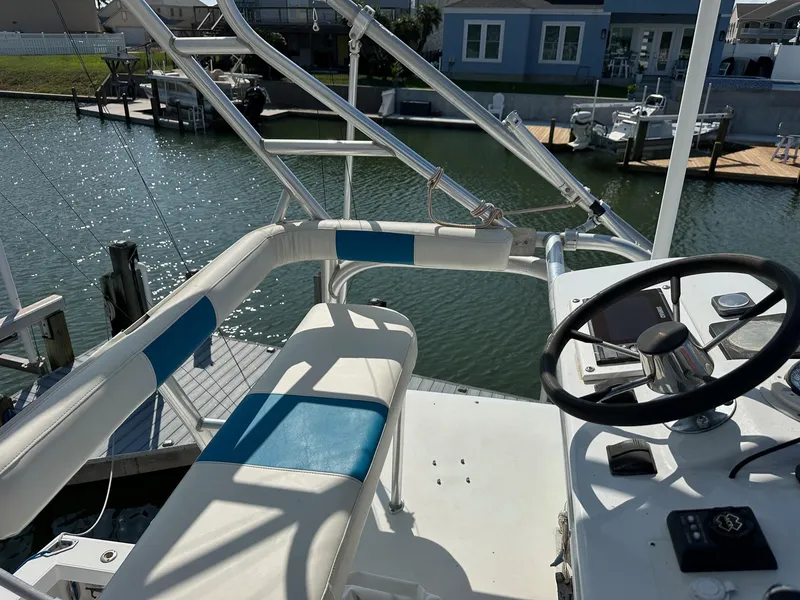 Slide: The Image of 2000 Cabo 31 Express boat helm with steering wheel and seating, docked by waterfront homes. - 11