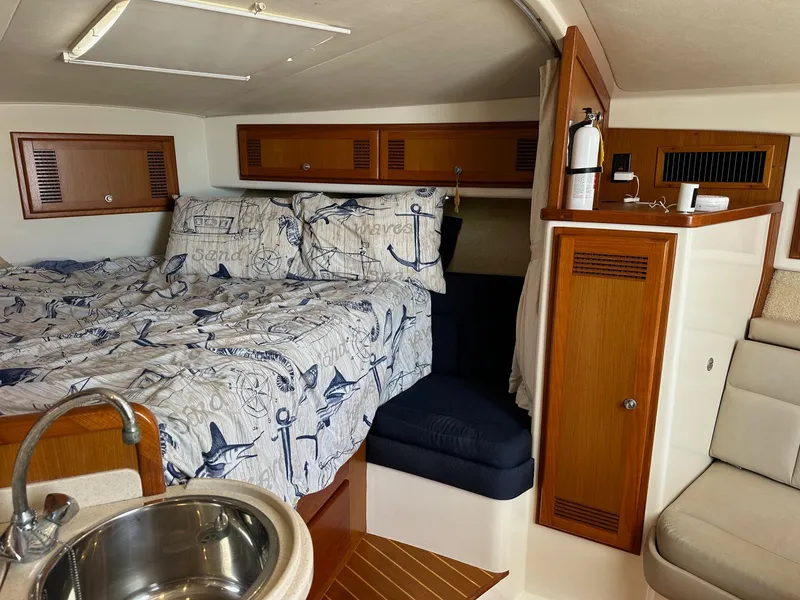 Slide: The Image of Cabo 31 Express 2000 cabin interior with nautical bedding and wooden cabinetry. - 17