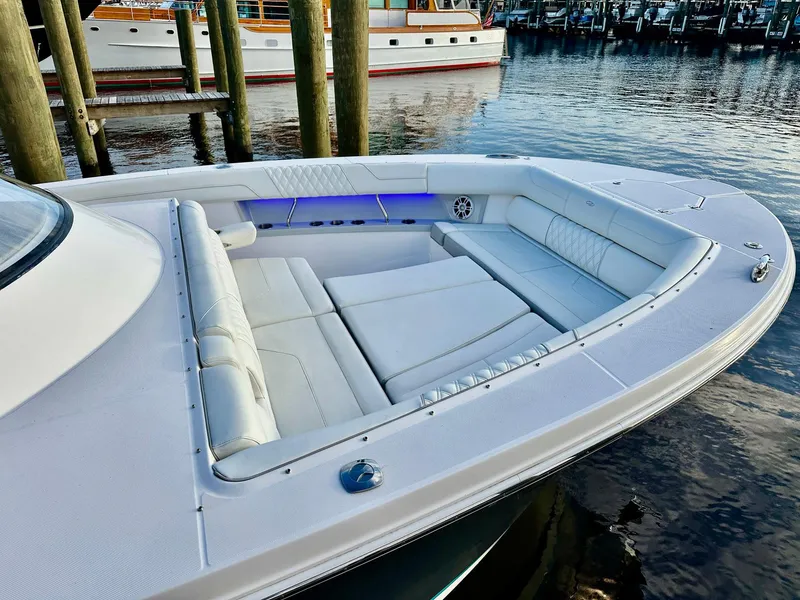 Slide: The Image of 2021 Regal 38 SAV boat with spacious white seating area docked at marina. - 14