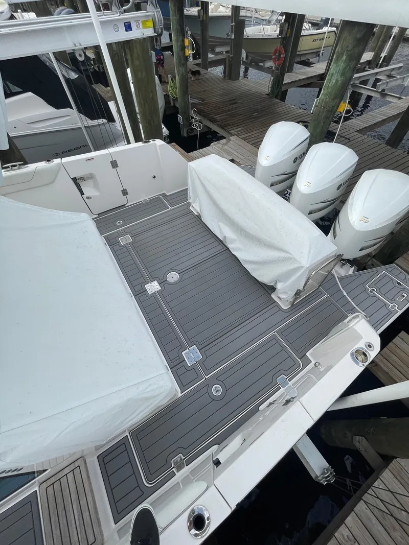 Slide: The Image of 2021 Regal 38 SAV boat with covered seating and triple outboard engines at a dock. - 48