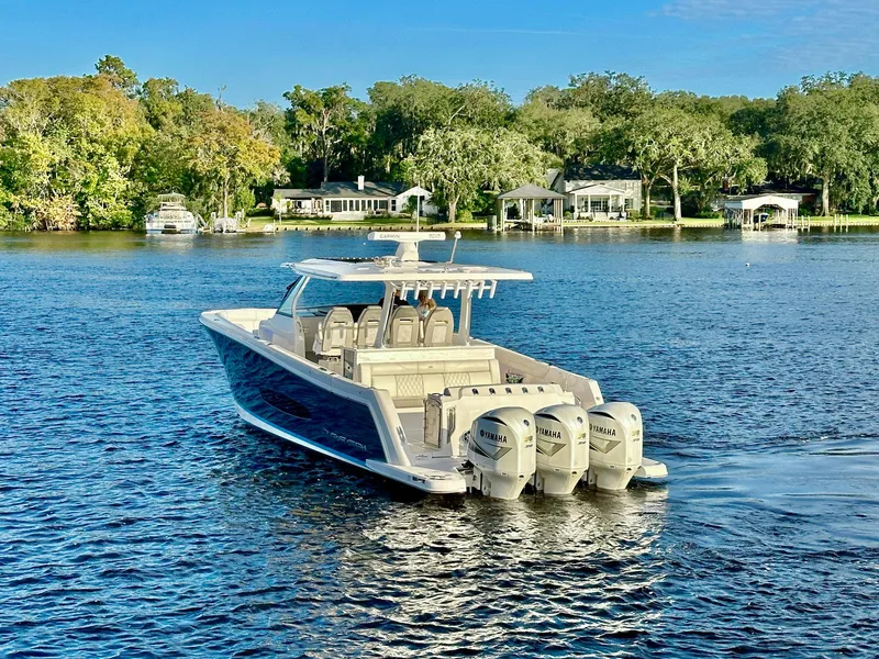 Slide: The Image of 2021 Regal 38 SAV boat cruising on a serene lake with lush greenery. - 5