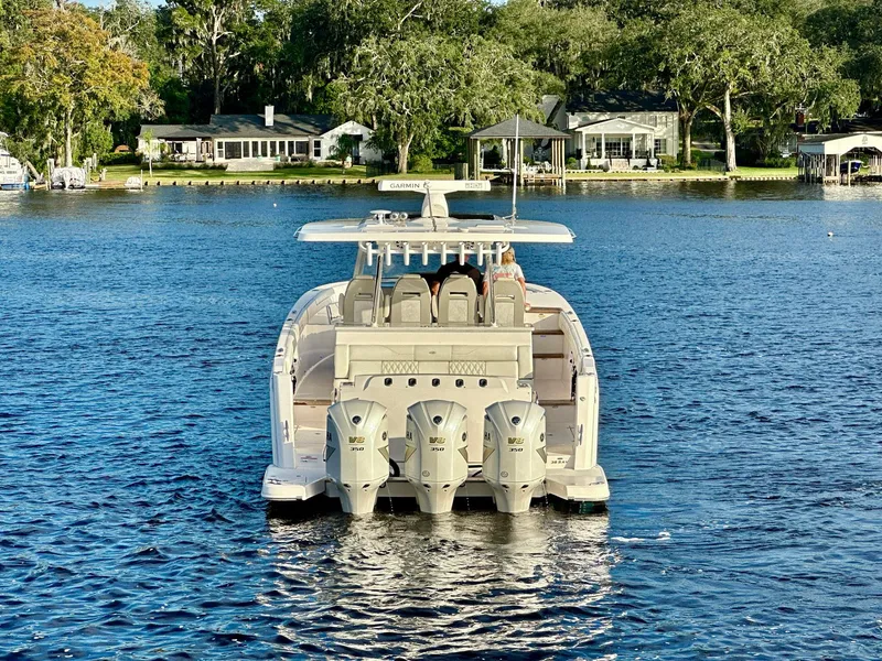 Slide: The Image of 2021 Regal 38 SAV boat on a serene lake with lush greenery. - 6