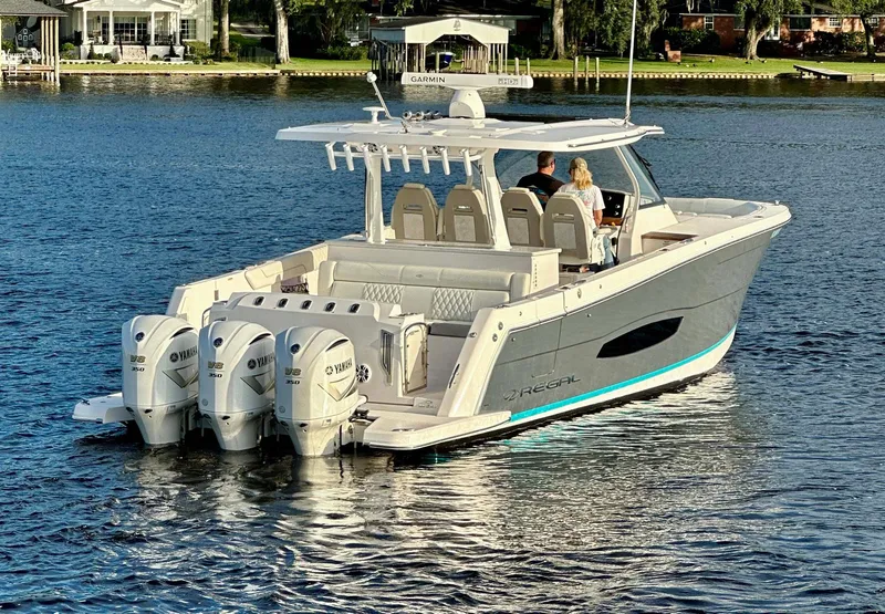 Slide: The Image of 2021 Regal 38 SAV boat with triple Yamaha engines on a serene lake. - 7