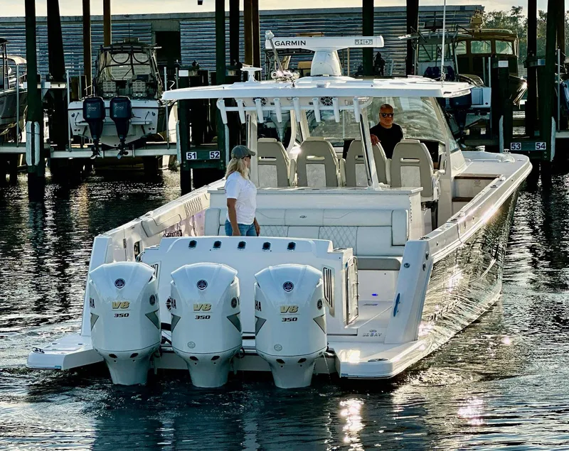 Slide: The Image of 2021 Regal 38 SAV boat with triple outboard engines docked at marina. - 9
