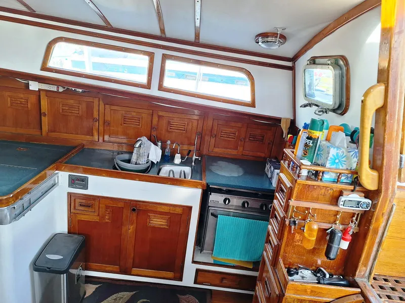 Slide: The Image of 1976 Cheoy Lee 40 Center Cockpit interior with wooden cabinetry and kitchen amenities. - 19