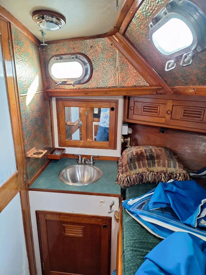 Slide: The Image of 1976 Cheoy Lee 40 Center Cockpit interior with sink, portholes, and wooden cabinetry. - 22