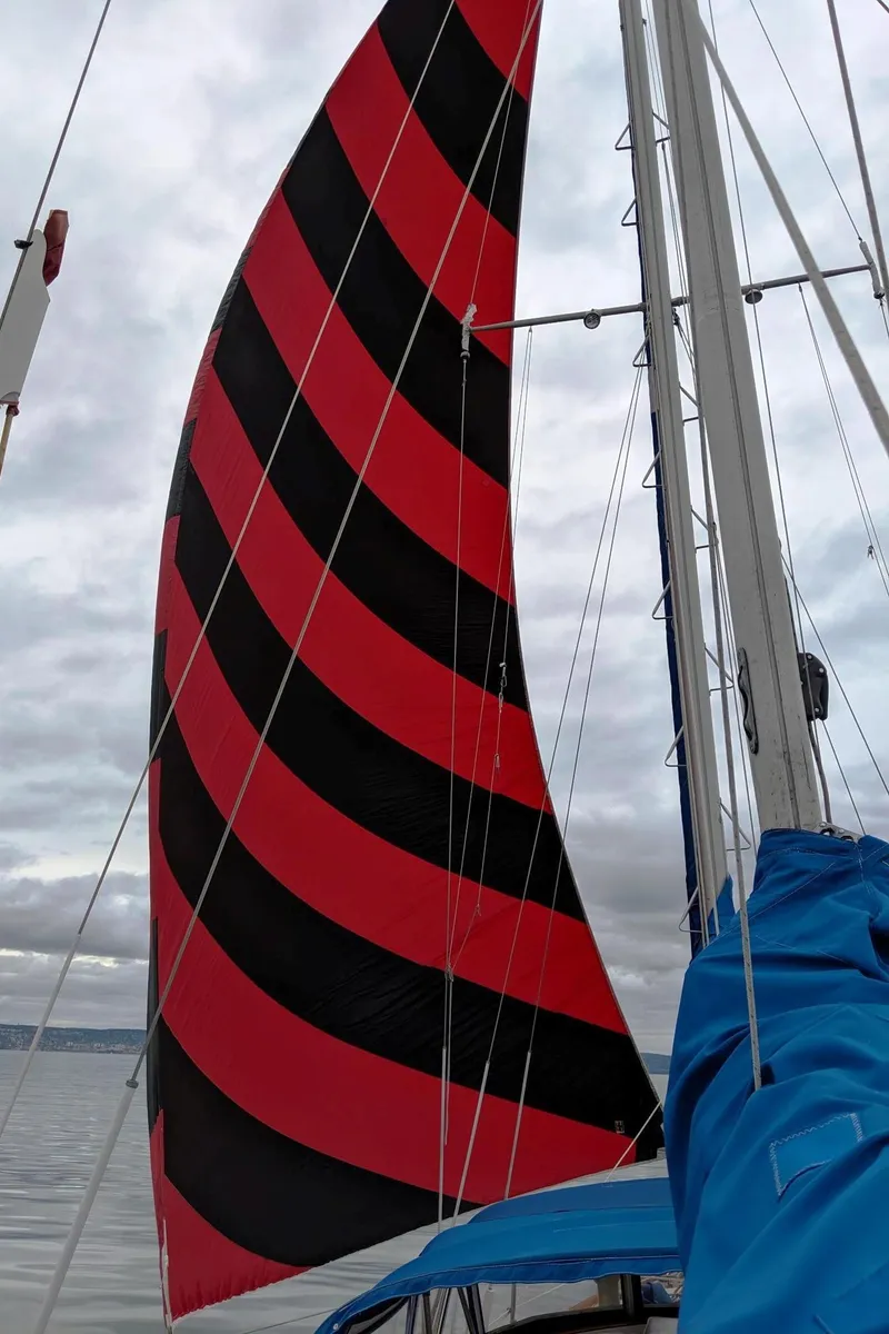 Slide: The Image of 1976 Cheoy Lee 40 Center Cockpit sailboat with striking red and black striped sail. - 40