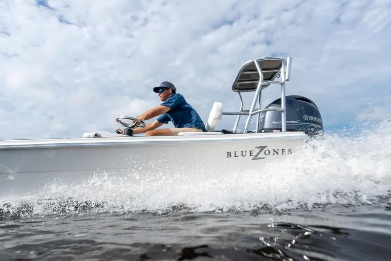 Slide: The Image of 2025 BlueZones Boatworks 16' Flats skiff cruising on water with driver. - 11
