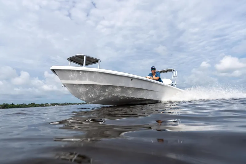 Slide: The Image of 2025 BlueZones Boatworks 16' Flats boat cruising on open water under cloudy skies. - 18