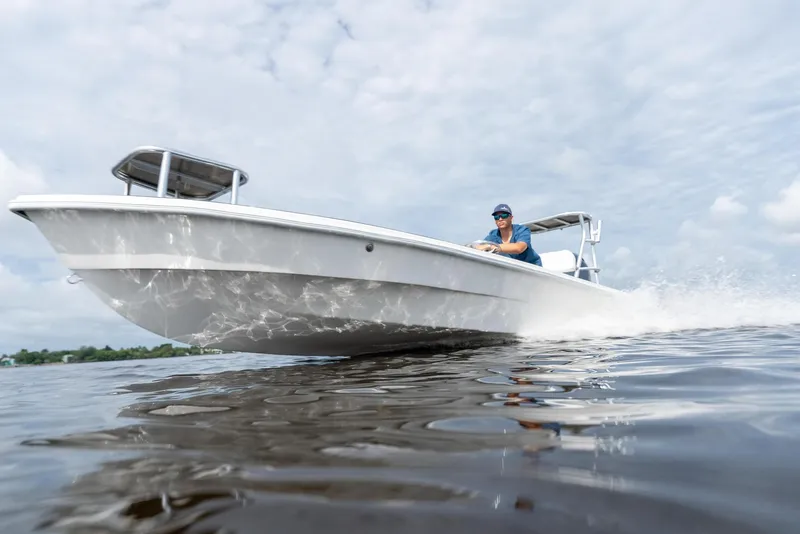 Slide: The Image of 2025 BlueZones Boatworks 16' Flats boat cruising on water under cloudy sky. - 19