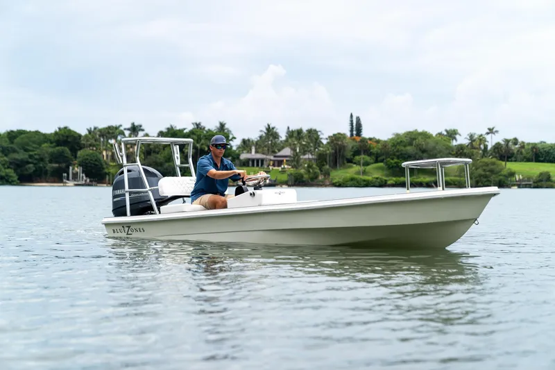 Slide: The Image of 2025 BlueZones Boatworks 16' Flats boat on calm water with driver. - 2