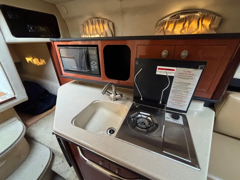 Slide: The Image of 2005 Sea Ray 260 Sundancer cabin kitchen with sink, stove, and microwave. - 30