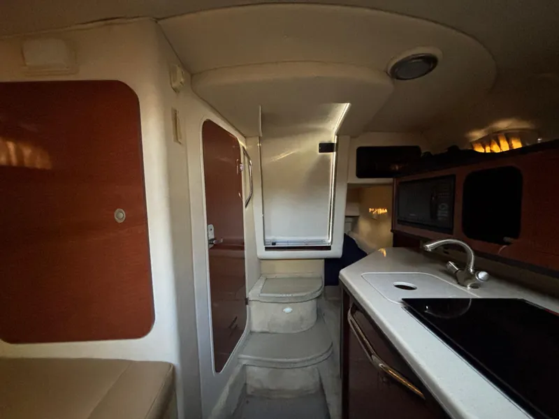 Slide: The Image of Interior of 2005 Sea Ray 260 Sundancer boat, featuring kitchenette and seating area. - 32