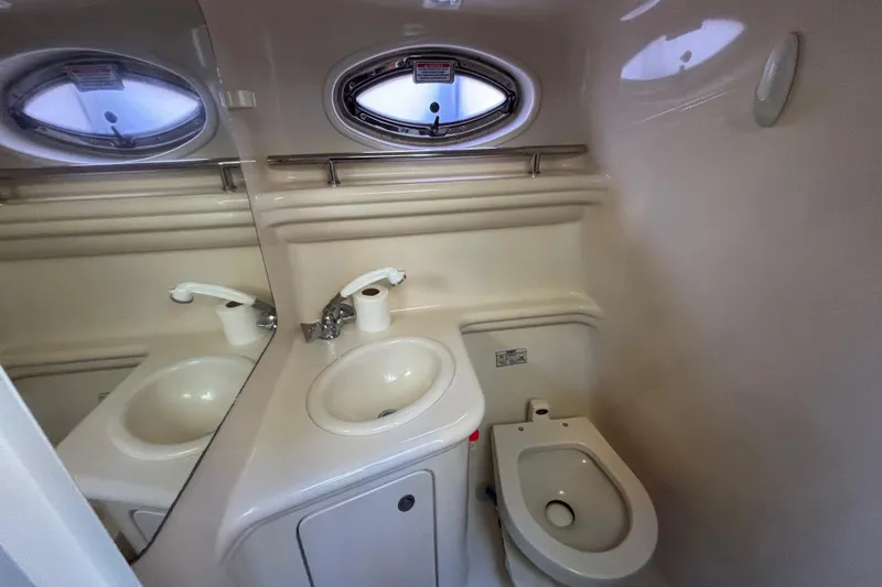 Slide: The Image of 2005 Sea Ray 260 Sundancer bathroom with sink, toilet, and porthole window. - 33