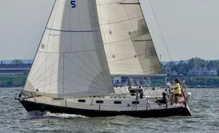 The Image of 1988 Tartan 31 sailboat navigating calm waters with full sails. - 0
