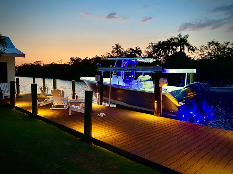 The Image of 2017 Sea Hunt Gamefish 27 boat docked at sunset, illuminated with blue lights. - 0