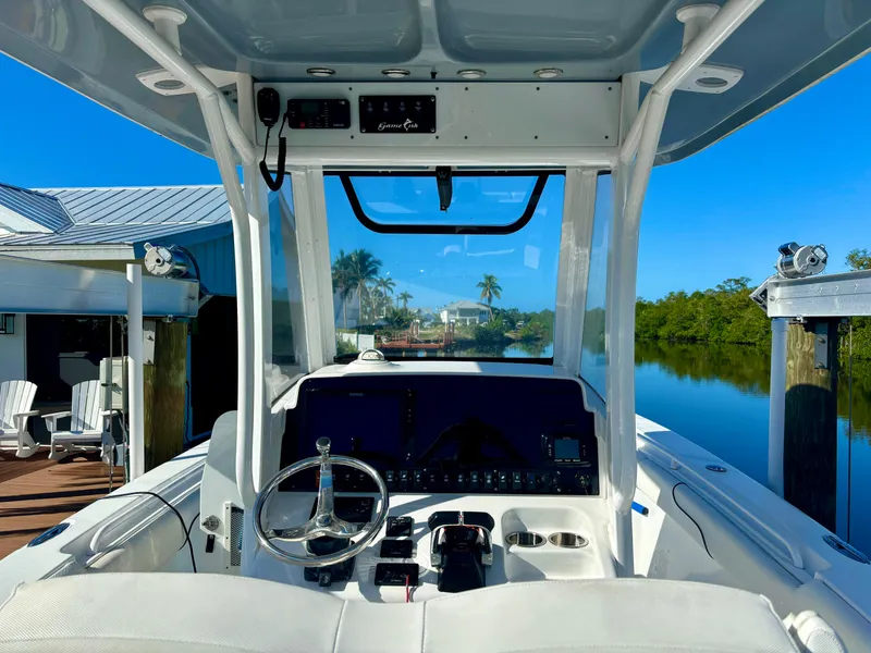 Slide: The Image of 2017 Sea Hunt Gamefish 27 boat interior with steering wheel, docked by a serene waterfront. - 3