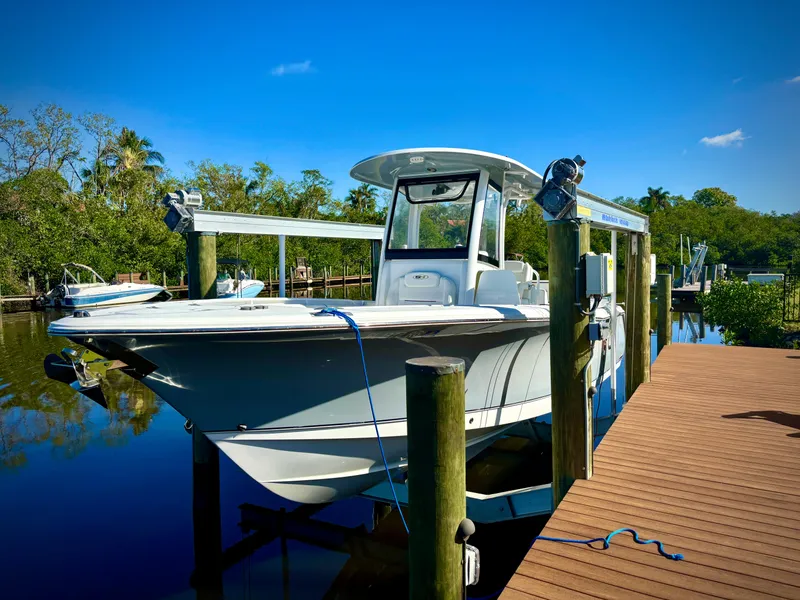 Slide: The Image of 2017 Sea Hunt Gamefish 27 boat docked on a sunny day, surrounded by lush greenery. - 4