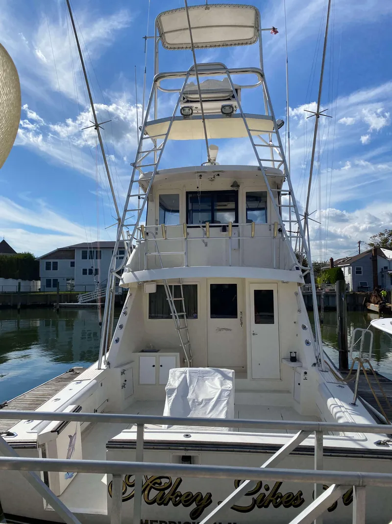 Slide: The Image of 1992 Henriques 50 Sportfisherman boat docked, featuring a spacious deck and tower. - 2