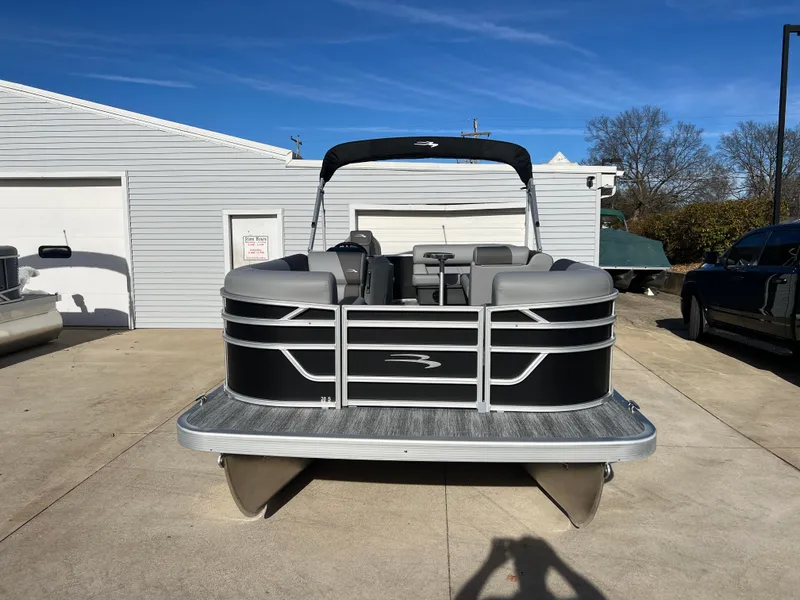 Slide: The Image of 2025 Bennington 20 SL pontoon boat parked outside a garage on a sunny day. - 2
