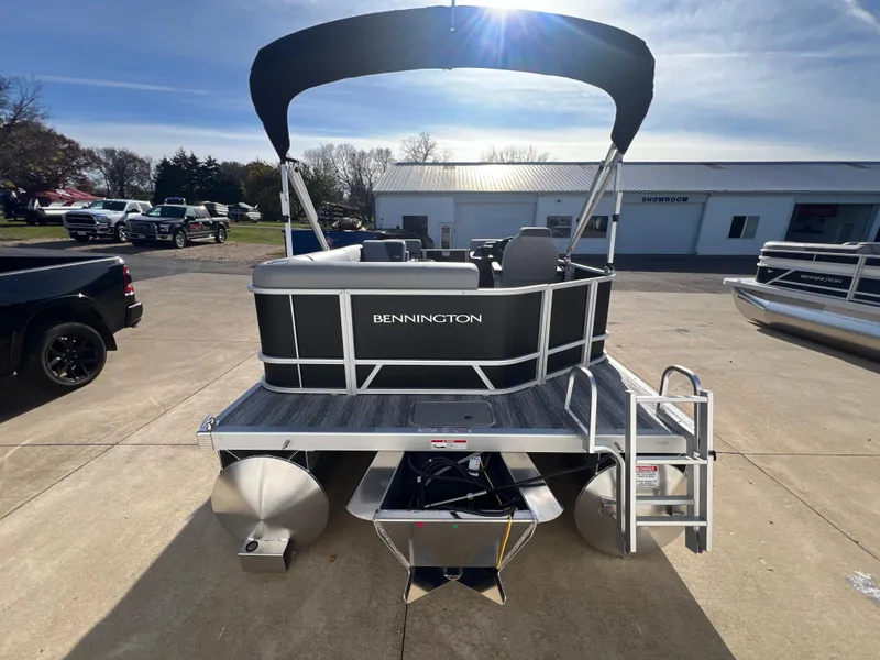 Slide: The Image of 2025 Bennington 20 SL pontoon boat with canopy, parked outdoors on a sunny day. - 6
