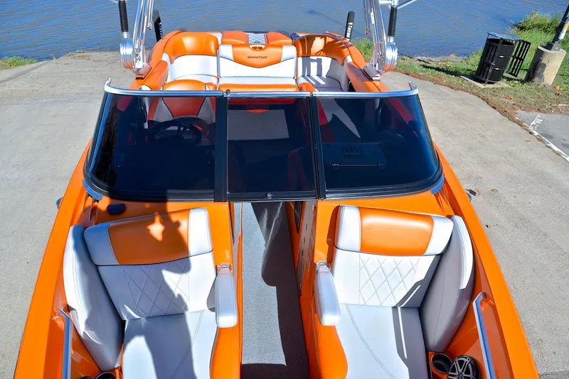 Slide: The Image of 2015 MasterCraft X23 boat with orange and white interior, docked by the water. - 20