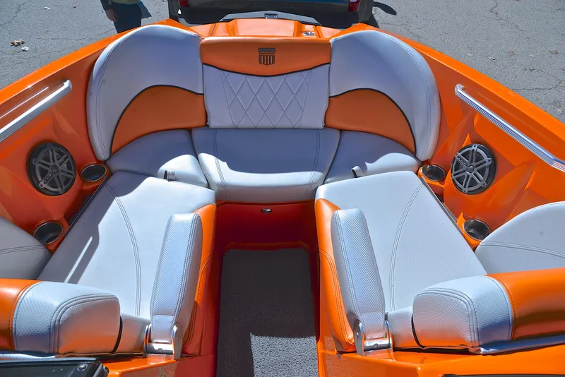 Slide: The Image of 2015 MasterCraft X23 boat interior with orange and white seating, featuring cup holders and speakers. - 21
