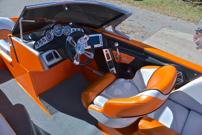 Slide: The Image of 2015 MasterCraft X23 boat interior with orange and gray seating, modern dashboard, and steering wheel. - 25