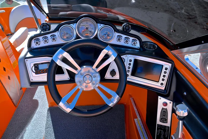 Slide: The Image of 2015 MasterCraft X23 dashboard with steering wheel, gauges, and controls in an orange interior. - 26