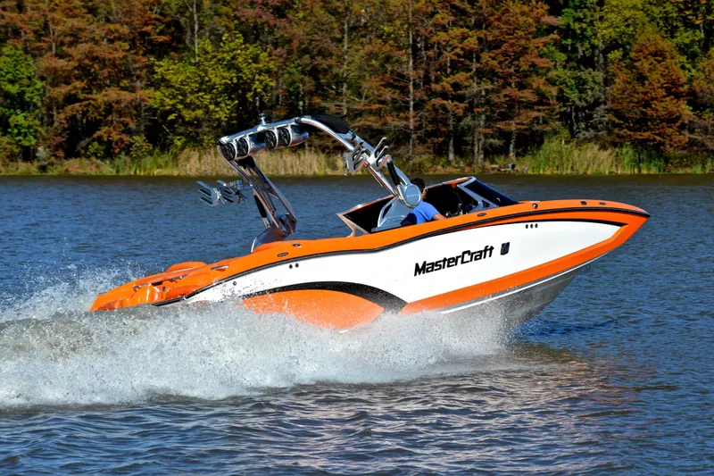 Slide: The Image of 2015 MasterCraft X23 boat speeding on a lake with trees in the background. - 5