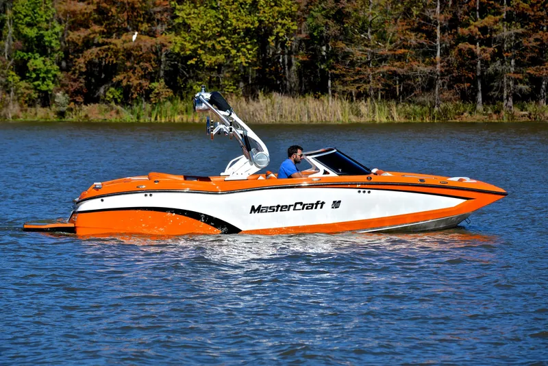 Slide: The Image of 2015 MasterCraft X23 boat on a lake with trees in the background. - 7