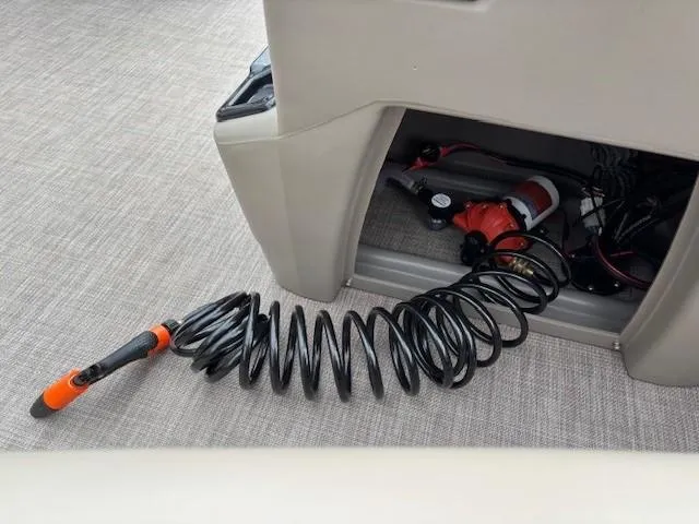 Slide: The Image of Sun Tracker Bass Buggy 18 DLX 2022 boat compartment with coiled hose and pump. - 16