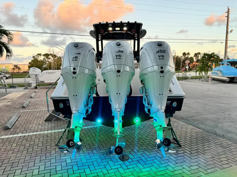 Slide: The Image of 2025 Edgewater 370 CC boat with triple 350 V6 engines, illuminated in a parking area. - 2