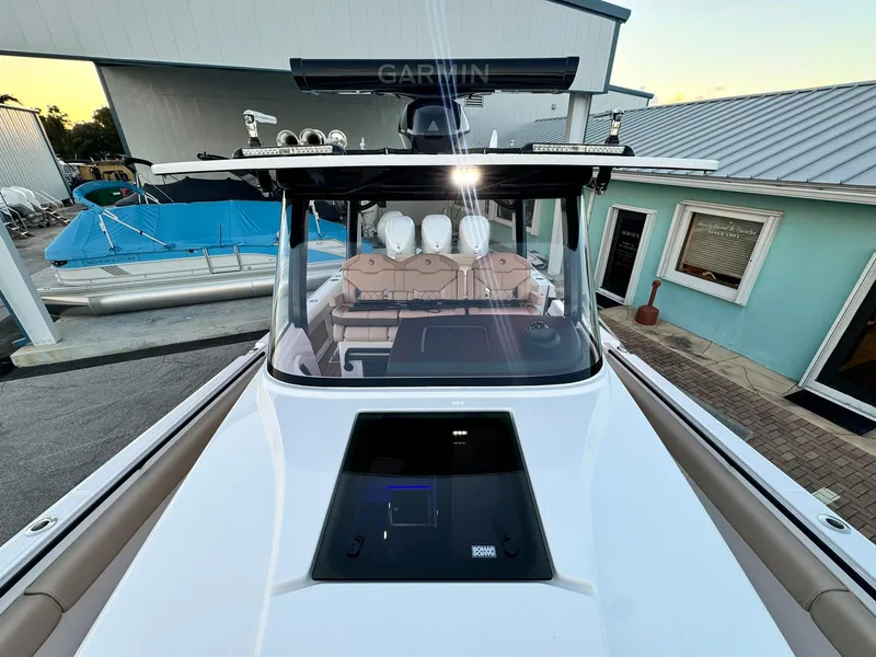 Slide: The Image of 2025 Edgewater 370 CC boat, sleek design, docked near blue building. - 32