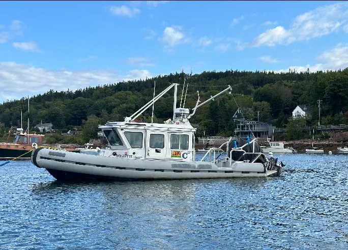 Slide: The Image of 2005 SAFE Boats Defender 25 on water, scenic background with trees and houses. - 0