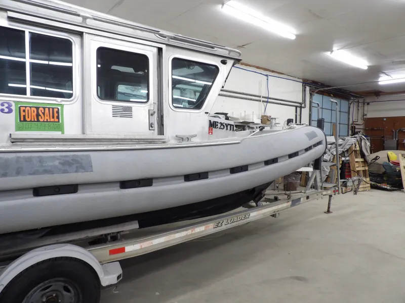 Slide: The Image of 2005 SAFE Boats Defender 25 for sale in a garage on a trailer. - 12